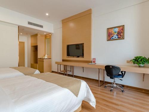 a hotel room with a bed and a desk with a television at GreenTree Inn Taian High-speed Railway Station Lingshan Avenue Business Hotel in Tai'an