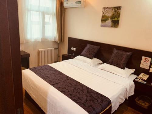a bedroom with a large bed with white sheets at GreenTree Inn Tianjin Huanghe Ave Guangkai Metro Station Express Hotel in Tianjin