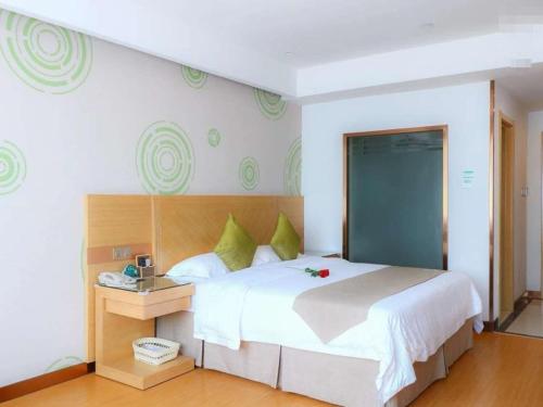een slaapkamer met een groot wit bed met groene kussens bij GreenTree Inn Anhui Fuyang Yingshang Yingyang Road Suzhou Manor Business Hotel in Jingzhuang