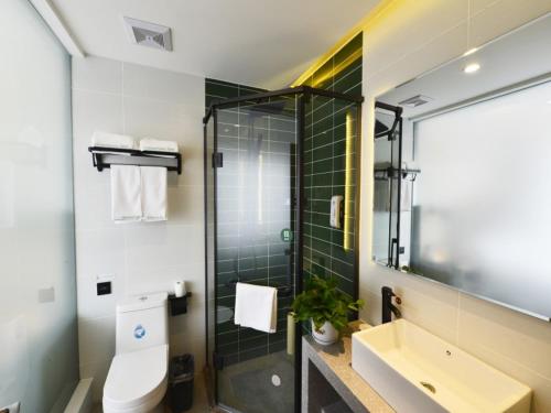 a bathroom with a toilet and a sink and a shower at GreenTree Inn Huludao Yuzhong County Central Road Smart Choice Hotel in Suizhong