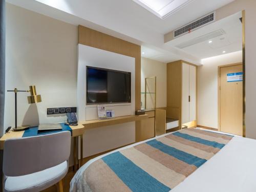 a hotel room with a bed and a flat screen tv at GreenTree Eastern Xuzhou High Speed Railway Station West Exit Station Hotel in Xuzhou