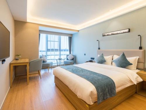 a bedroom with a large bed and a living room at GreenTree Eastern Xuzhou High Speed Railway Station West Exit Station Hotel in Xuzhou