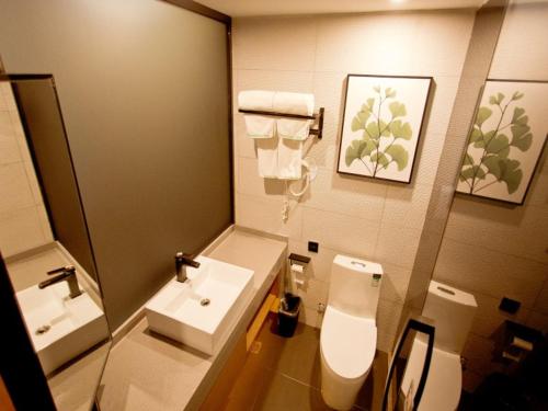 W łazience znajduje się umywalka, toaleta i lustro. w obiekcie GreenTree Inn Fuyang City Yingzhou District Kuixing Road Business Hotel w Fuyang