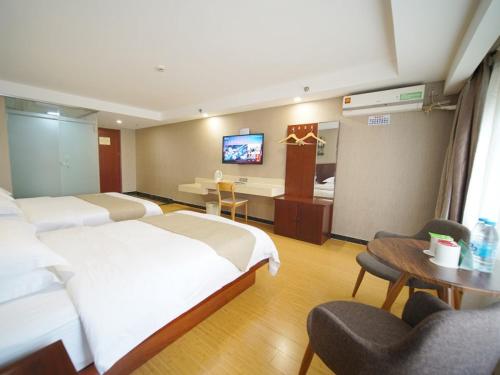 a hotel room with two beds and a desk at GreenTree Inn Shanghai Baoshan Yanghang Shuichan Road Hotel in Baoshan