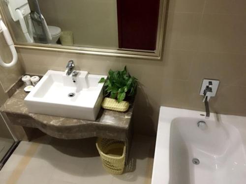a bathroom with a sink and a mirror and a tub at GreenTree Inn Jiangsu Xuzhou Food Town International Exhibition and Convention Center Business Hotel in Xuzhou