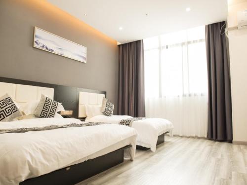 a hotel room with two beds and a window at Shell Wuxi Huishan DistrictWanda Plaza Yanqiao Subway Station Hotel in Wuxi