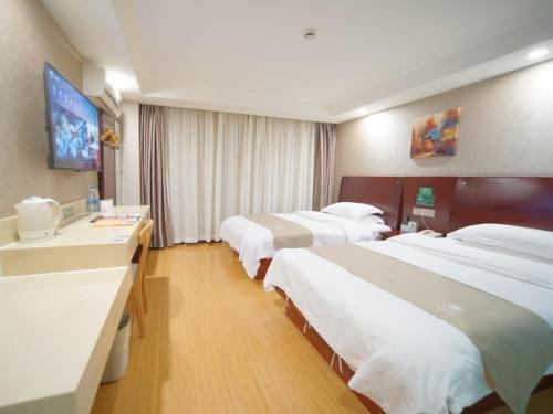 a hotel room with three beds and a desk at GreenTree Inn Shanghai Baoshan Yanghang Shuichan Road Hotel in Baoshan