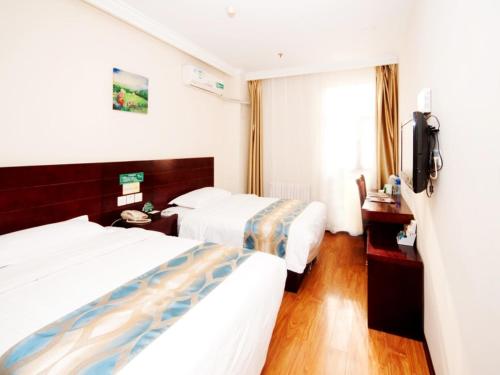a hotel room with two beds and a television at GreenTree Inn Tianjin Huanghe Ave Guangkai Metro Station Express Hotel in Tianjin