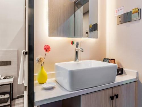 a bathroom with a white sink and a yellow vase at Shell Xi'an Yanta District Jixiang Village Subway Entrance Hotel in Xi'an