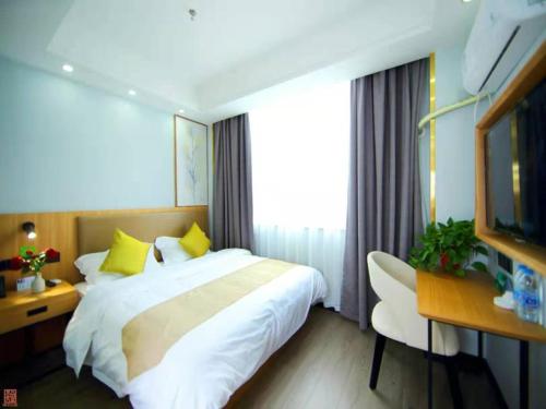 een slaapkamer met een bed, een bureau en een raam bij GreenTree Inn Wuxi Jiangyin Changjing Town Selected Hotel in Wuxi