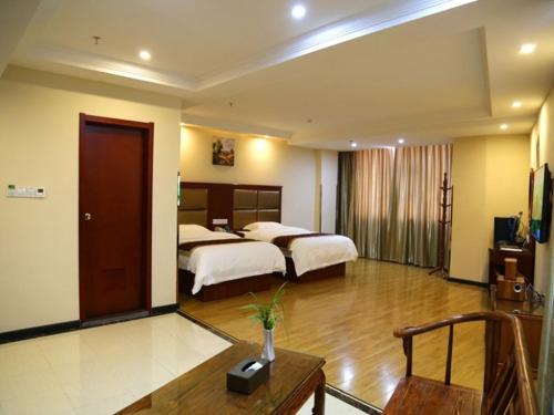 um grande quarto de hotel com duas camas e uma mesa em GreenTree Inn HuNan JiShou LongShan Yuelu Avenue Business Hotel em Longshan