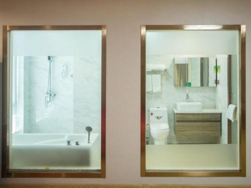 a bathroom with a tub and a sink and a toilet at GreenTree Inn Zhoushan Baiquan Colorful Plaza Express Hotel in Zhoushan