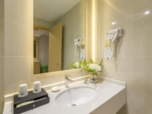 a bathroom with a sink and a mirror at GreenTree Inn Xuzhou Ou Shasha Building Materials City Express Hotel in Xuzhou