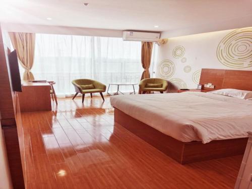 a bedroom with a bed and a desk and chairs at GreenTree Inn Liaocheng Economic Development Zone Huitong Logistics Park Express Hotel in Liaocheng