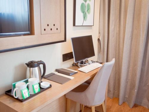 a desk with a computer on top of it at GreenTree Inn Fuyang City Yingzhou District Kuixing Road Business Hotel in Fuyang