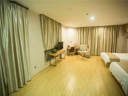 a hotel room with a bedroom with a bed and a desk at GreenTree Inn Zhoushan Baiquan Colorful Plaza Express Hotel in Zhoushan
