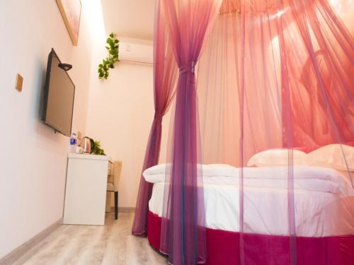 a bedroom with a bed with a pink canopy at Shell Wuxi Huishan DistrictWanda Plaza Yanqiao Subway Station Hotel in Wuxi