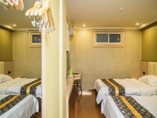 a hotel room with three beds and a desk at GreenTree Inn Jinhua Railway Station Express Hotel in Jinhua
