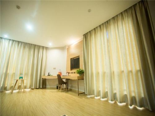 a living room with curtains and a desk and a table at GreenTree Inn Zhoushan Baiquan Colorful Plaza Express Hotel in Zhoushan
