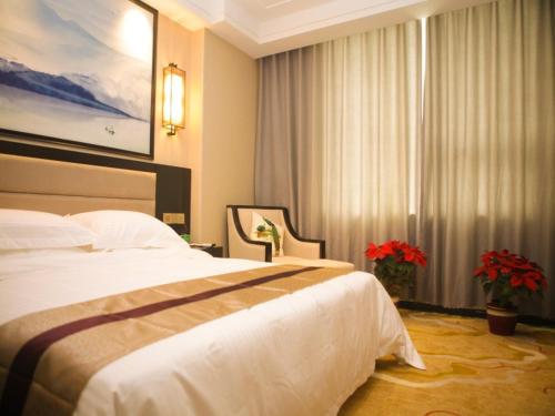 a hotel room with a large bed and flowers at GreenTree Alliance Texas Ningjin County Zhengyang Road Debai Plaza Hotel in Dezhou