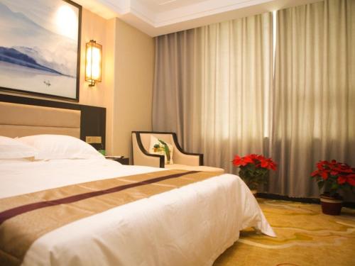a hotel room with a bed and a window with red flowers at GreenTree Alliance Texas Ningjin County Zhengyang Road Debai Plaza Hotel in Dezhou