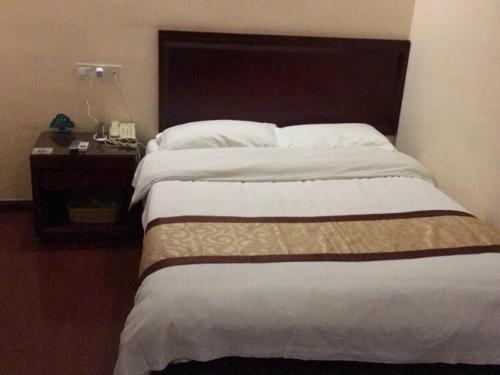 a bedroom with a large bed with a wooden headboard at GreenTree Inn Jiangsu Suzhou International Education Zone Shihu Express Hotel in Suzhou