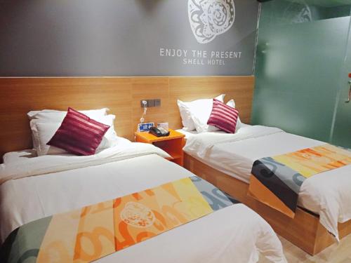 a room with two beds and a sign that reads enjoy the present still hurt at Shell Tai'an Taishan District Xinhuacheng International Plaza Hotel in Tai'an