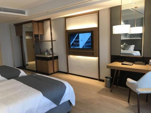 a hotel room with a bed and a desk and a television at GreenTree Eastern Xuzhou High Speed Railway Station West Exit Station Hotel in Xuzhou