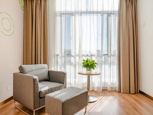 a living room with a chair and a table and a window at GreenTree Inn Taian High-speed Railway Station Lingshan Avenue Business Hotel in Tai'an