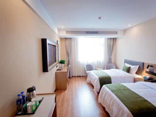 a hotel room with two beds and a television at GreenTree Inn Fuyang City Yingzhou District Kuixing Road Business Hotel in Fuyang
