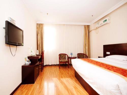 a hotel room with a bed and a flat screen tv at GreenTree Inn Tianjin Huanghe Ave Guangkai Metro Station Express Hotel in Tianjin