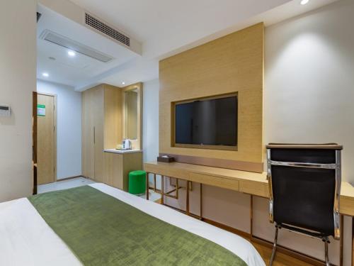 a bedroom with a bed and a desk with a television at GreenTree Eastern Xuzhou High Speed Railway Station West Exit Station Hotel in Xuzhou