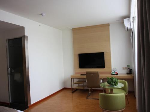 a living room with a table and a tv at GreenTree Inn Zaozhuang High Speed Rail Station Express Hotel in Taozhuang