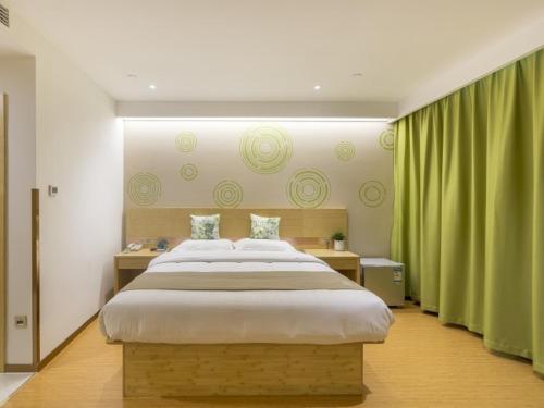 徐州的住宿－格林豪泰徐州高铁站东广场智选酒店，一间卧室配有一张带绿色窗帘的大床
