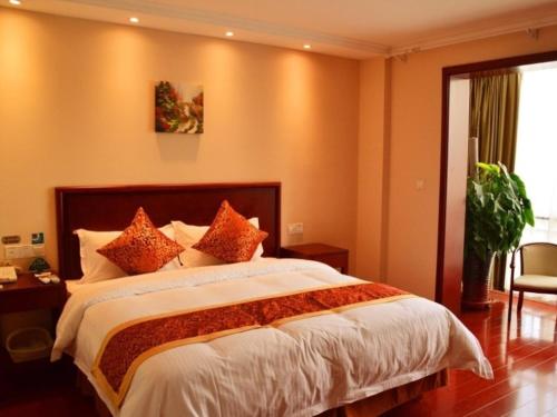 a bedroom with a large bed with orange walls at GreenTree Inn ShanXi ChangZhi Bus Passenger Station XiHuan Road Business Hotel in Changzhi