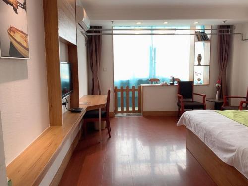 a hotel room with a bed and a desk and a television at GreenTree Inn ShanDong Jinan Railway Station Provincial Hospital Jinger Road Express Hotel in Jinan