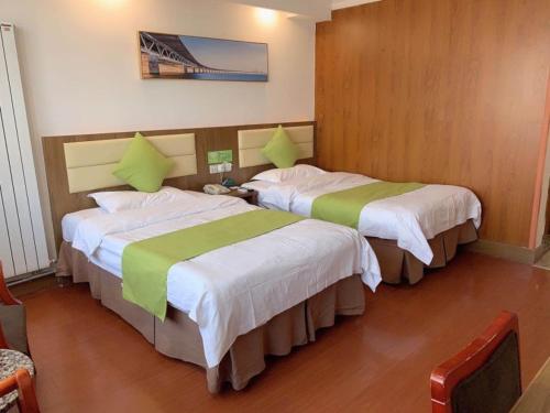 a hotel room with two beds with green sheets at GreenTree Inn ShanDong Jinan Railway Station Provincial Hospital Jinger Road Express Hotel in Jinan