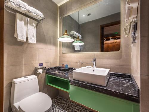 a bathroom with a sink and a toilet and a mirror at GreenTree Eastern Xuzhou High Speed Railway Station West Exit Station Hotel in Xuzhou