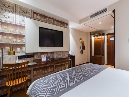a hotel room with a large bed and a flat screen tv at GreenTree Eastern Xuzhou High Speed Railway Station West Exit Station Hotel in Xuzhou