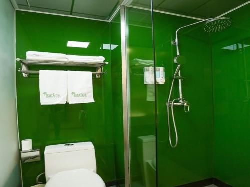 a green bathroom with a toilet and a shower at Vatica Hefei Lujiang Road Hotel in Hefei