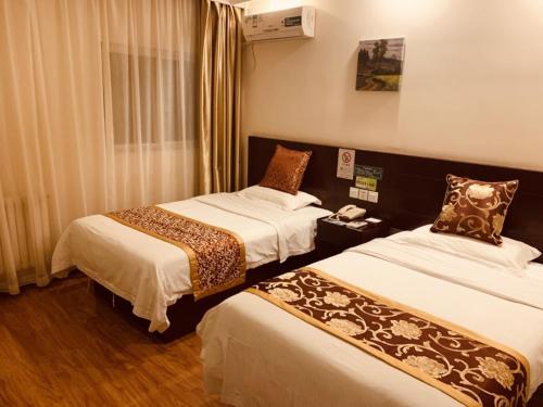 a hotel room with two beds and a phone at GreenTree Inn Tianjin Huanghe Ave Guangkai Metro Station Express Hotel in Tianjin
