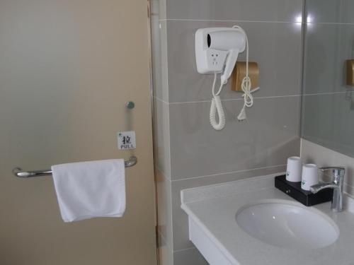 a bathroom with a sink and a phone on the wall at GreenTree Inn Zaozhuang High Speed Rail Station Express Hotel in Taozhuang
