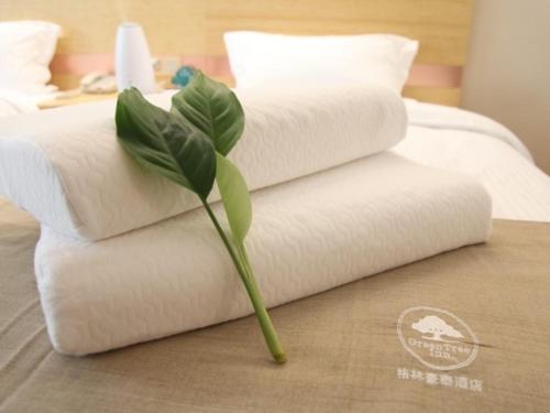 a stack of white towels sitting on top of a bed at GreenTree Inn Xuzhou Ou Shasha Building Materials City Express Hotel in Xuzhou