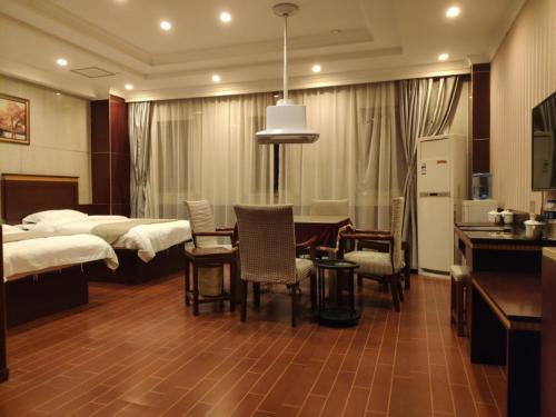 a bedroom with two beds and a table and chairs at GreenTree Inn Shanghai Fengxian Xidu Business Hotel in Fengxian