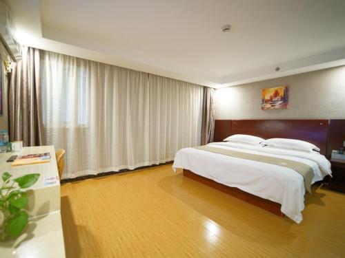 a bedroom with a large bed with white sheets at GreenTree Inn Shanghai Baoshan Yanghang Shuichan Road Hotel in Baoshan