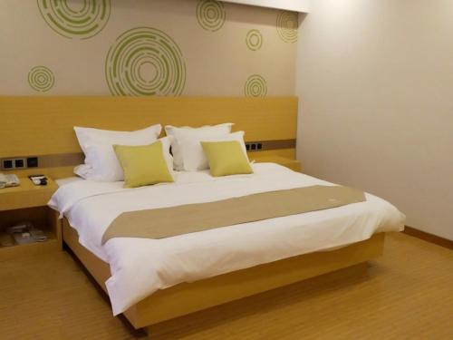 a bedroom with a large white bed with yellow pillows at GreenTree Inn HuaiAn Area for development Shenzhen East Road Express Hotel in Huai'an