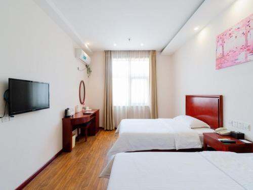 a hotel room with two beds and a television at GreenTree Inn Henan Zhengzhou Chengnan Road Bojue Business Hotel in Zhengzhou