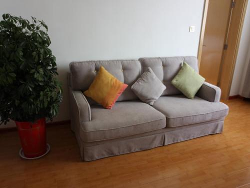 a couch with pillows on it in a living room at GreenTree Inn Zaozhuang High Speed Rail Station Express Hotel in Taozhuang