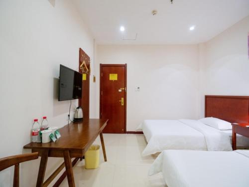 a room with two beds and a table and a tv at GreenTree Inn Henan Zhengzhou Chengnan Road Bojue Business Hotel in Zhengzhou