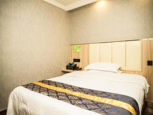 a bedroom with a large bed with a yellow stripe on it at GreenTree Inn Jinhua Railway Station Express Hotel in Jinhua